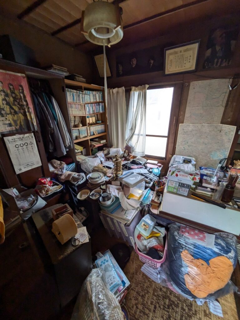 横浜市港北区仲手原2丁目　再建築不可　残置物あり物件　建物内写真（和室）テーブル上を生活雑貨が埋め尽くしている