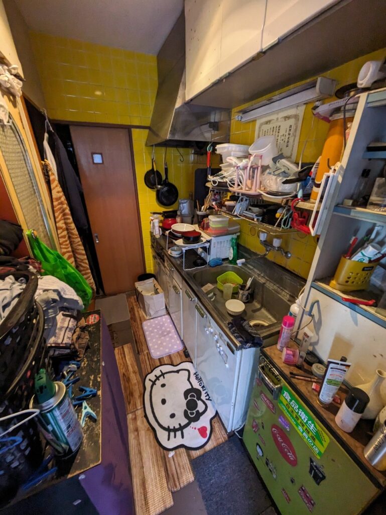 百合ヶ丘1丁目　残置物あり物件　建物内写真（キッチン）シンクに放置されたままの食器、雑貨など生活用品が多く残されている